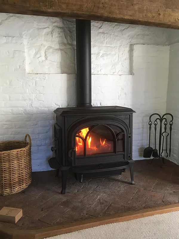 Lit woodburner stove and flue set in fireplace