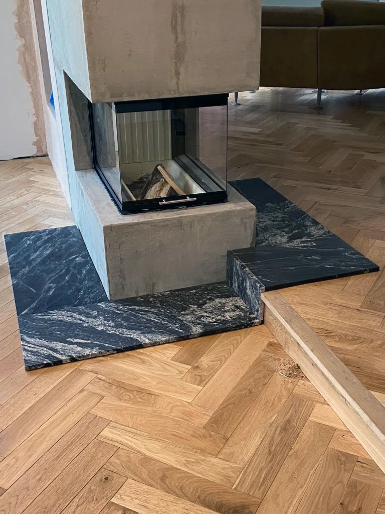 Ultra-modern glass fireplace installed in wall divider with marble hearth