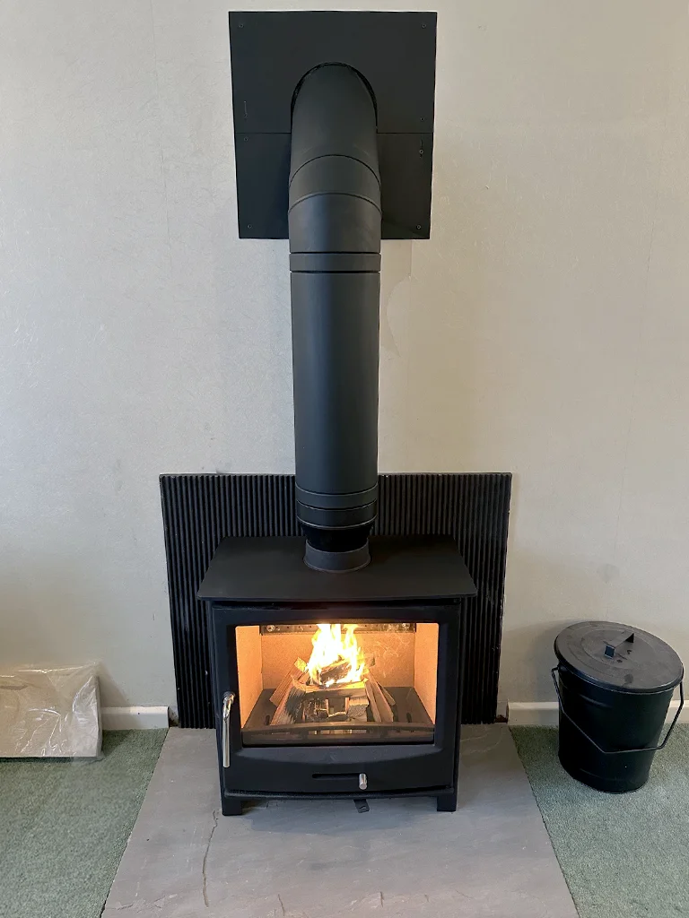 Lit woodburner stove and flue set in fireplace